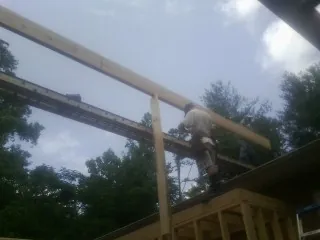Carpenter setting a ridge beam over a new addition frame — Ice Dam Removal by Roofing Brothers in Greentown