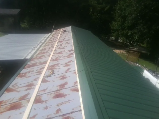 Old rusted panels beside newly installed green metal roofing — Wind Damage Roof Repair by Roofing Brothers in Greentown