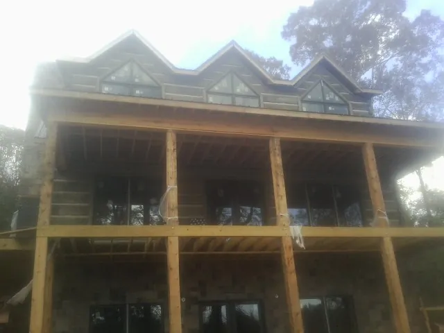 Dormers and porch framing on a large log home under construction — Roof Coating work by our crew in Greentown
