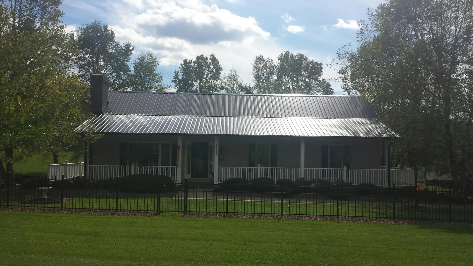 Gray metal roof on a brick ranch with a full width front porch — Gutter Guard Installation work by our crew in Greentown