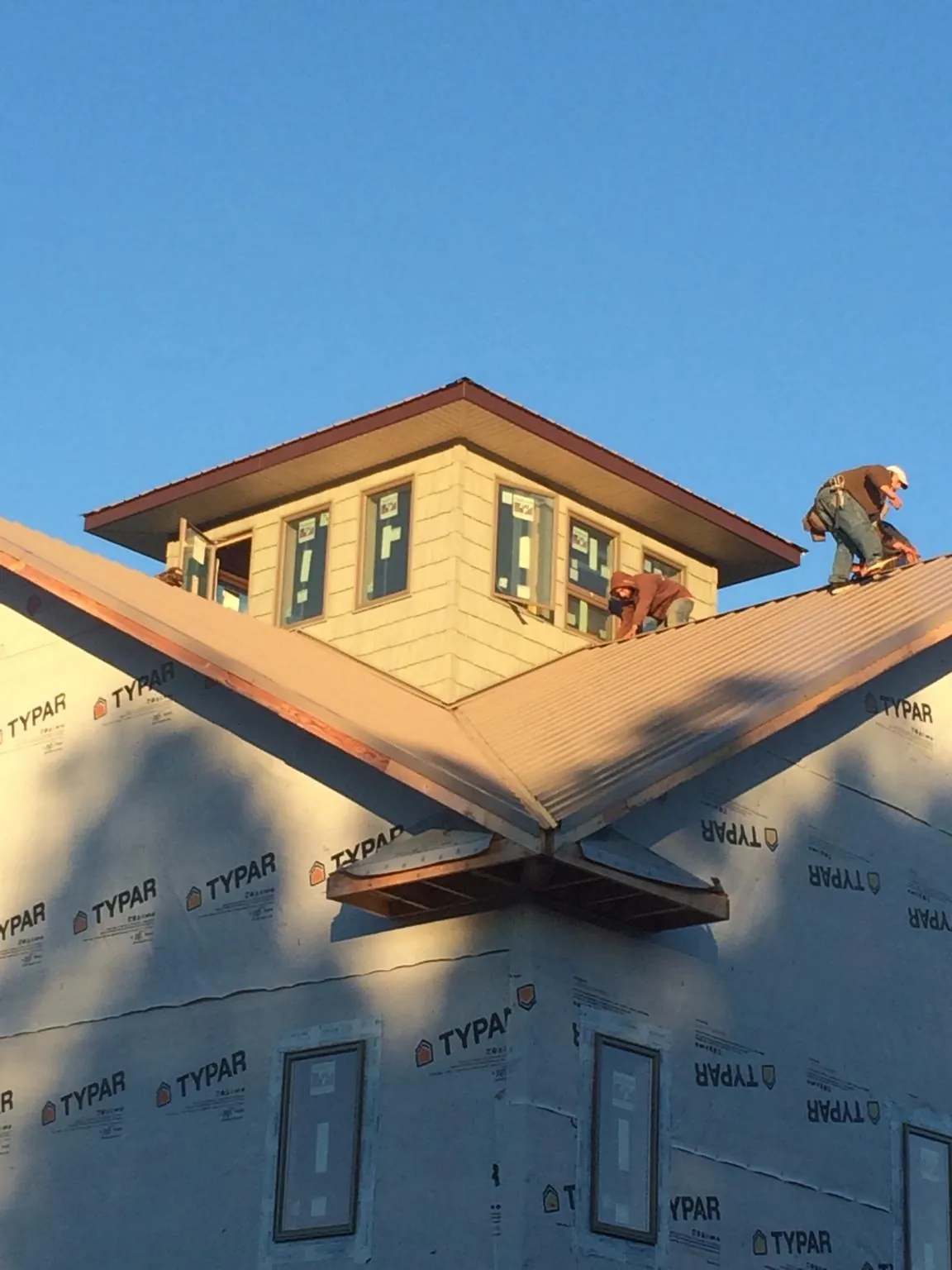 Roofers working around a rooftop cupola on a new metal roof at sunset — Roof Waterproofing in Greentown by Roofing Brothers